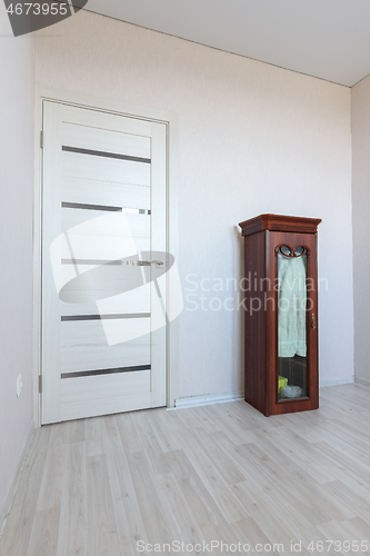 Image of Fragment of an empty room interior with a small cabinet and a door