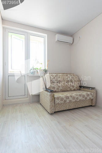 Image of The interior of the room - a sofa, air conditioning and access to a balcony with plastic windows and a door