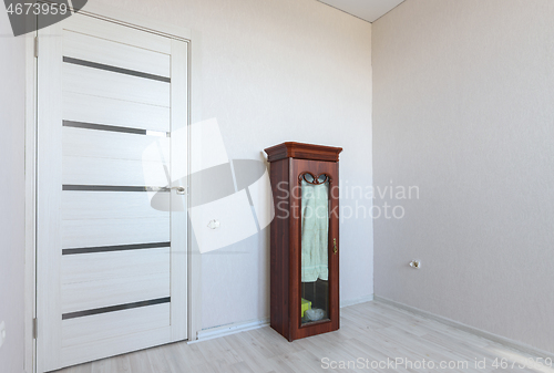Image of A fragment of a small bedroom in an apartment with poor furniture, a view of the front door and a locker