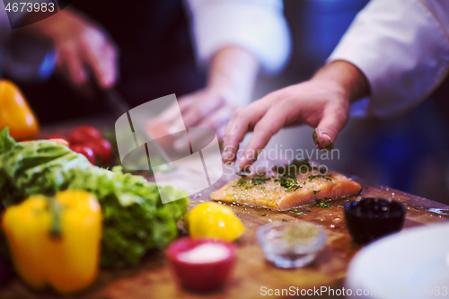 Image of Chef hands preparing marinated Salmon fish