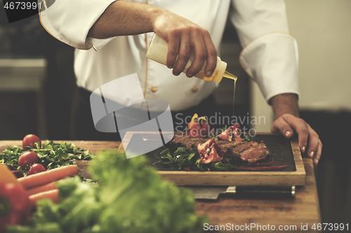 Image of Chef finishing steak meat plate