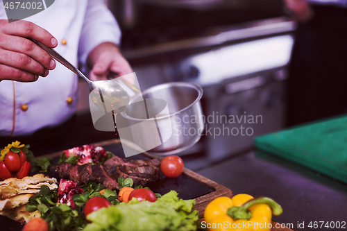 Image of Chef hand finishing steak meat plate