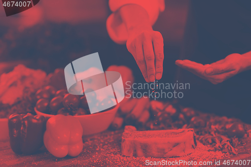 Image of Chef putting salt on juicy slice of raw steak