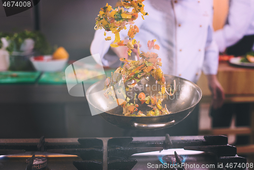 Image of chef flipping vegetables in wok