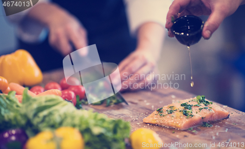 Image of Chef hands preparing marinated Salmon fish