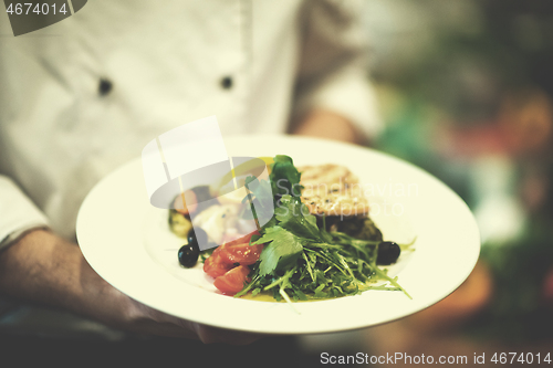 Image of Chef hands holding dish of fried Salmon fish fillet