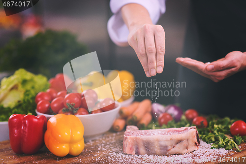 Image of Chef putting salt on juicy slice of raw steak