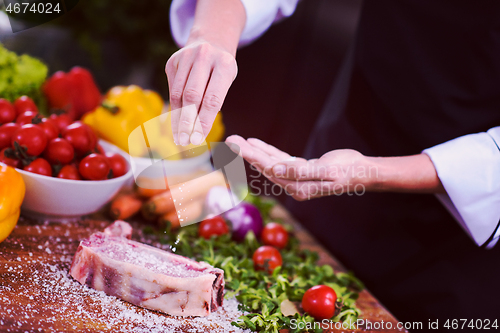 Image of Chef putting salt on juicy slice of raw steak