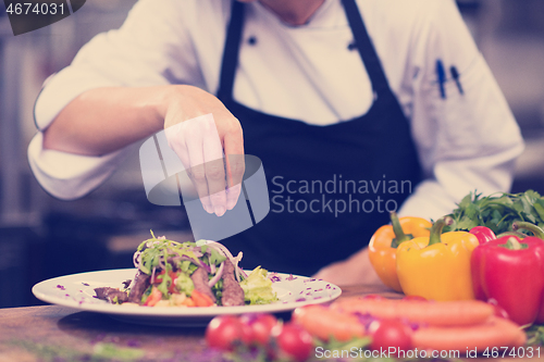 Image of cook chef decorating garnishing prepared meal