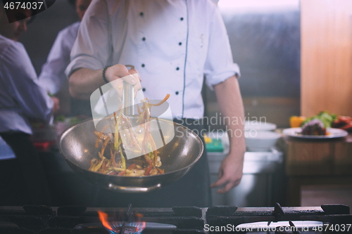 Image of chef flipping vegetables in wok