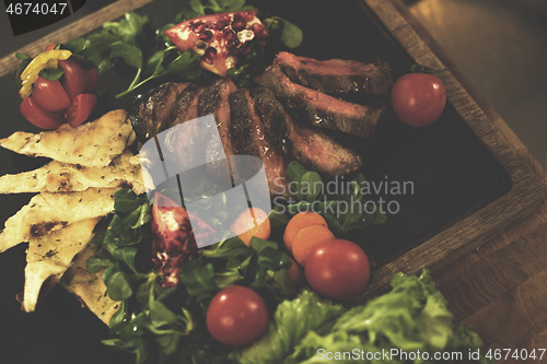 Image of Juicy slices of grilled steak on wooden board