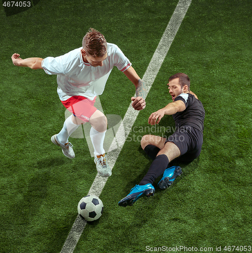 Image of Football players tackling ball over green grass background