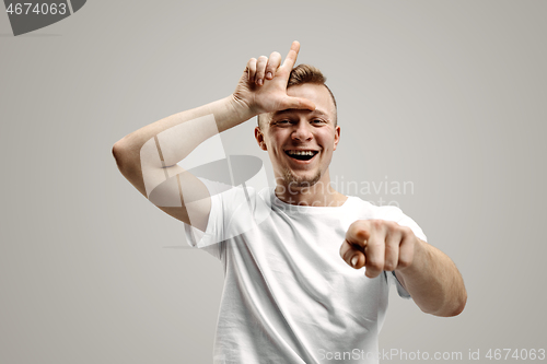 Image of Losers go home. Portrait of happy guy showing loser sign over forehead