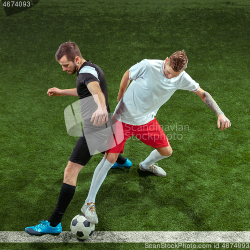 Image of Football players tackling ball over green grass background