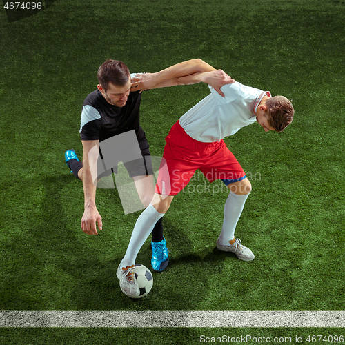 Image of Football players tackling ball over green grass background