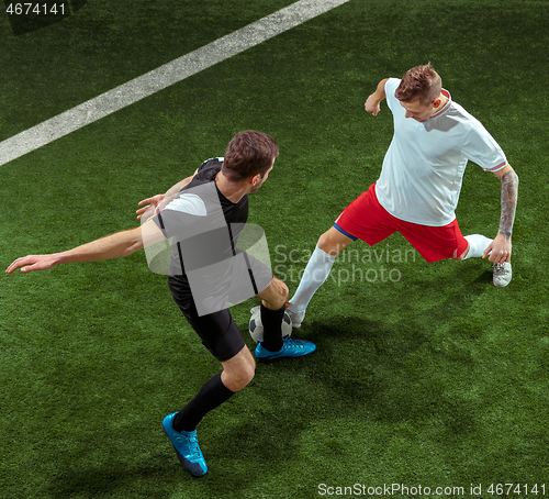 Image of Football players tackling ball over green grass background