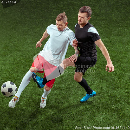 Image of Football players tackling ball over green grass background