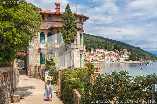 Image of Female tourist walking along Adriatic sea coast relaxing on vacation in Moscenicka Draga, Istria, Croatia.