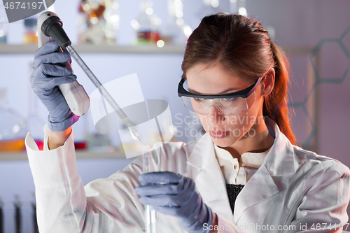 Image of Young scientist pipetting in life science laboratory.