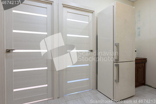 Image of Two interior doors in the apartment, there is a refrigerator on the right