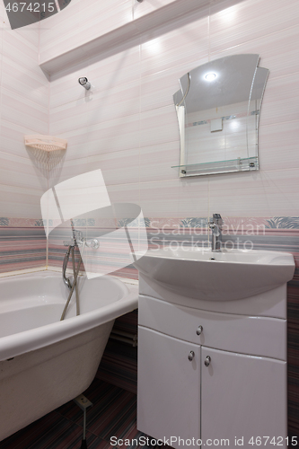 Image of A fragment of the interior of a conventional bathroom with a washbasin and an acrylic bathtub