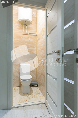 Image of Open door to a small toilet, a water heater is located upstairs