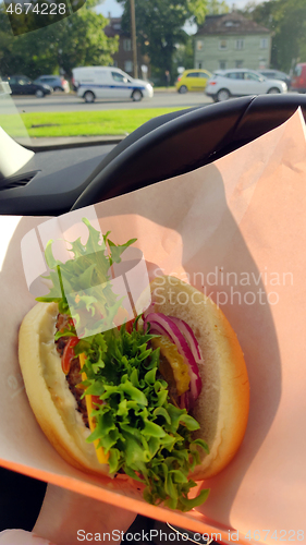 Image of Somebody eating gourmet burger in car