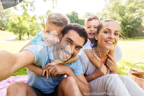 Image of family having picnic and taking selfie at park