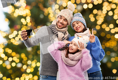 Image of happy family taking selfie over christmas lights