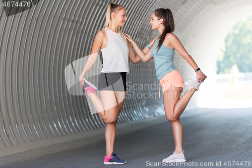 Image of women with fitness trackers stretching outdoors