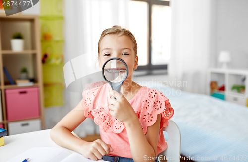 Image of student girl with magnifier and notebook at home