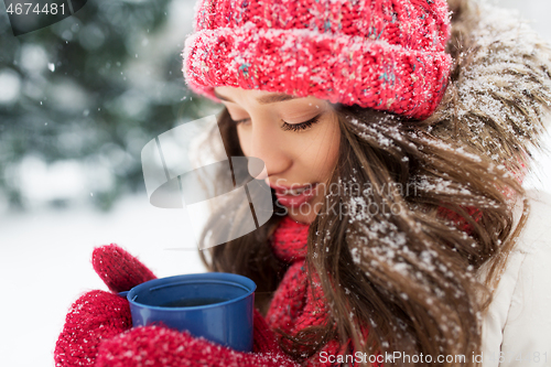 Image of happy young woman with tea cup in winter park