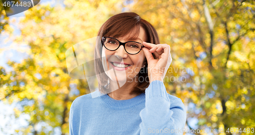 Image of portrait of old woman in glasses over autumn park