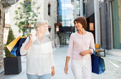 Image of senior women with shopping bags walking in city