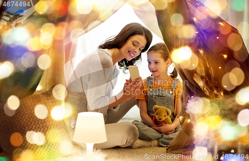 Image of happy family with smartphone in kids tent at home