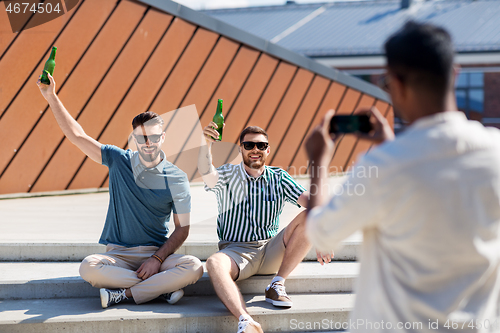 Image of man photographing friends drinking beer on street