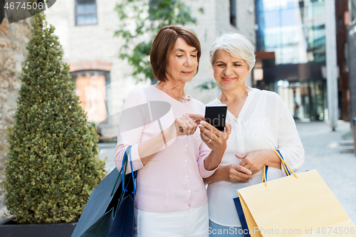 Image of old women with shopping bags and cellphone in city