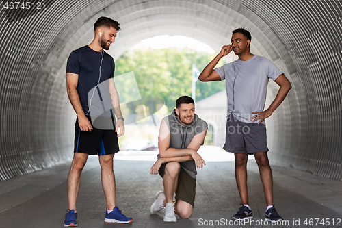 Image of male friends with earphones training outdoors