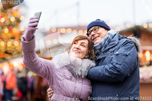 Image of senior couple taking selfie at christmas market