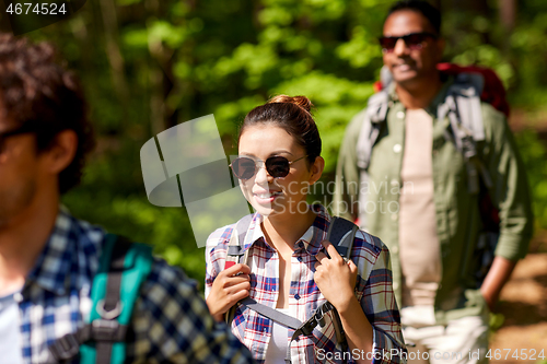 Image of group of friends with backpacks hiking in forest