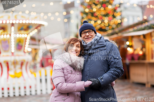 Image of happy senior couple hugging at christmas market