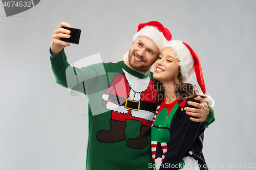 Image of happy couple in christmas sweaters taking selfie