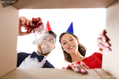 Image of couple in party hats opening birthday gift box