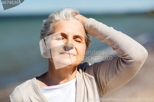 Image of portrait of senior woman enjoying sun on beach