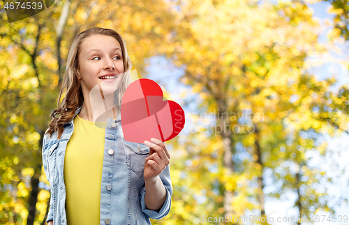 Image of smiling teenage girl with red heart in autumn park