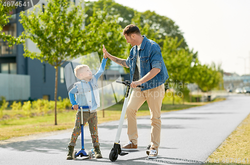 Image of father and son with scooters making high five