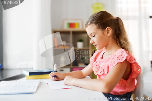 Image of student girl with book writing to notebook at home