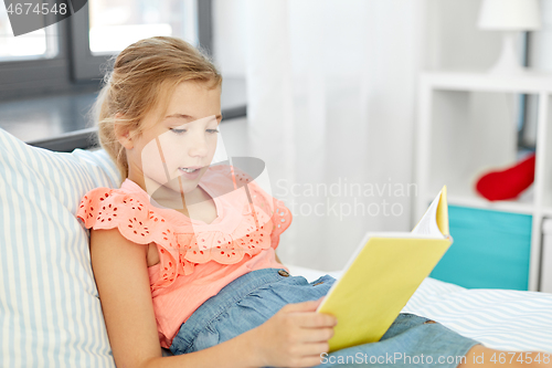 Image of happy little girl reading book at home