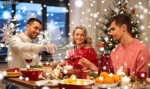 Image of happy friends drinking red wine at christmas party