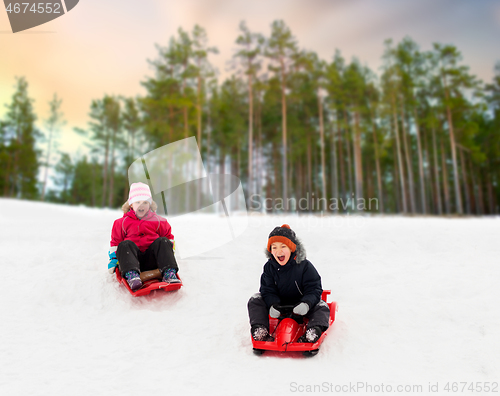 Image of happy kids sliding on sleds down hill in winter